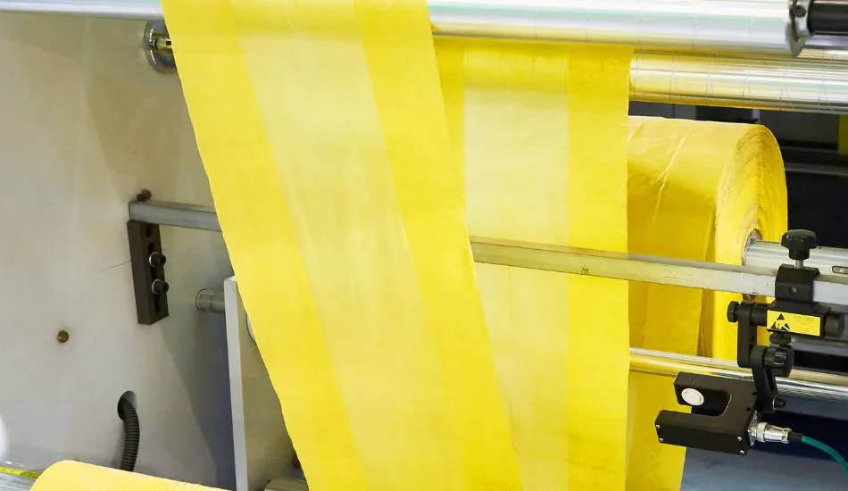Yellow polythene film running through rollers on a production line